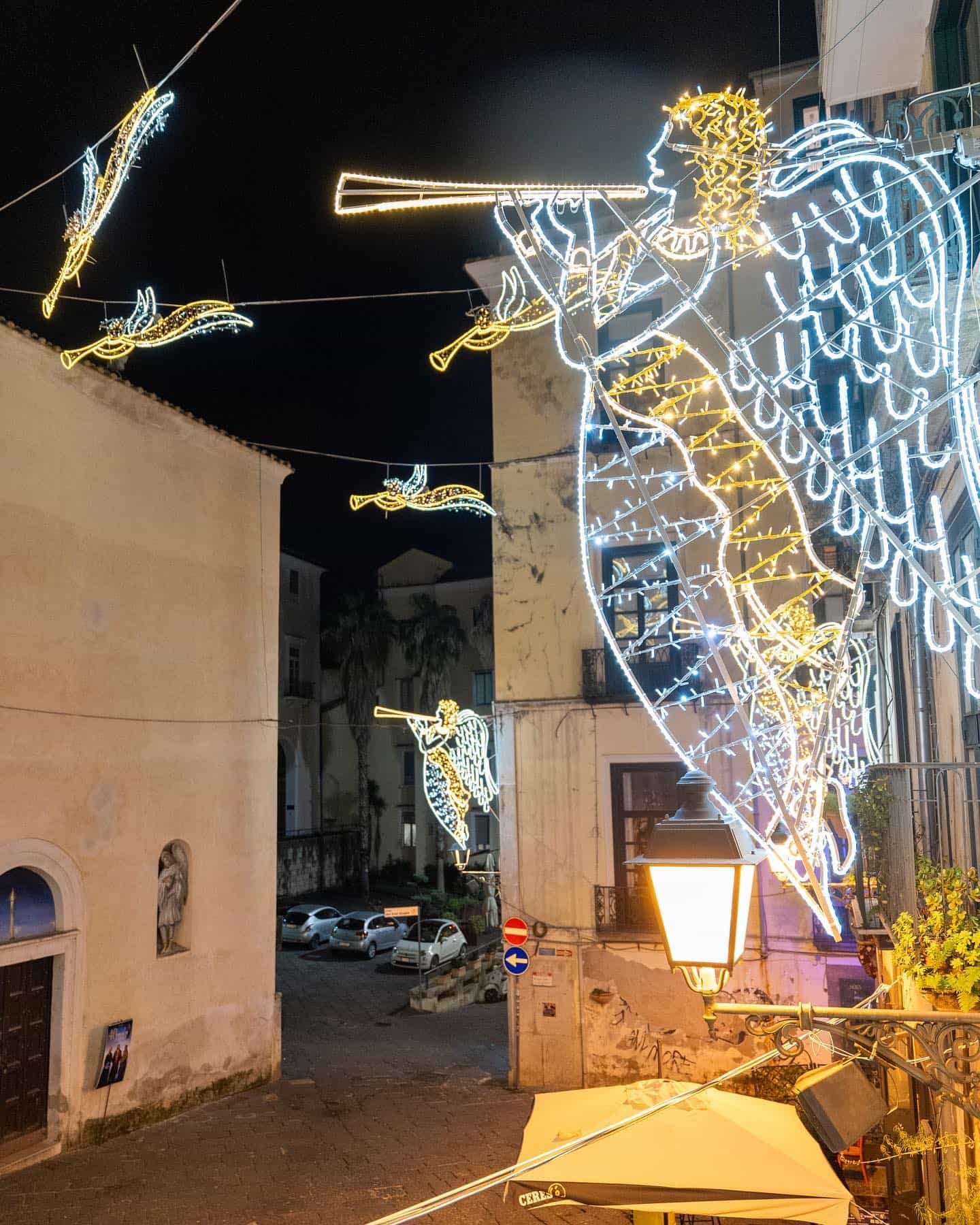 Gli angeli luminosi delle Luci d'Artista sospesi sopra la via, di sera